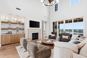 A spacious living area with a fireplace, modern furniture, and large windows offering a view.