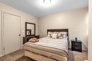 A bedroom with a bed, a nightstand, a dresser, and a mirror. - Niagara Falls Getaway (Niagara Falls)