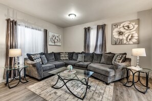 A modern living room with a sectional sofa, glass coffee table, and two lamps. - Lovely 2-bedroom townhome in Niagara Falls (Niagara Falls)