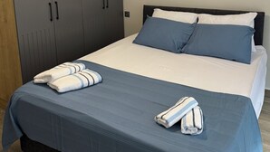Un dormitorio con cama, almohadas, una manta, una toalla y un armario.