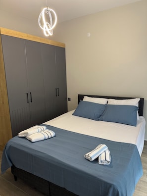 A bedroom with a bed, pillows, a blanket, a towel, and a wardrobe.