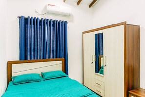 Ein Schlafzimmer mit Bett, Kleiderschrank, Spiegel und einem Fenster mit Vorhängen.