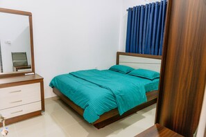 Ein Schlafzimmer mit Bett, Kommode, Spiegel und einem Fenster mit Vorhängen.