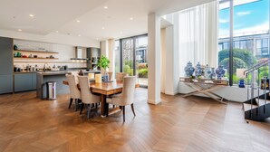 A modern kitchen with a dining area, large windows, and a view of the outside. - Luxury 4-Bed Duplex Penthouse (London)