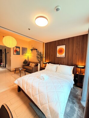 Ein Hotelzimmer mit einem großen Bett, einer Couch, einem kleinen Tisch, einer Lampe und einem an der Wand befestigten Kunstwerk.