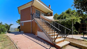 A two-story building with a brick facade, a balcony, and a staircase leading to the upper floor. - Poetto Beach | 5 Min Walk [WiFi & AC] (Cagliari)