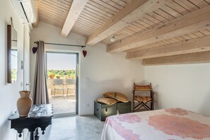 Ein Zimmer mit einem Bett, einem Tisch mit einer Vase, einem Koffer und einem Stuhl.