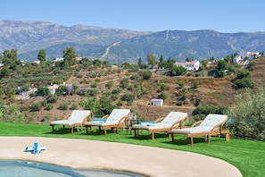 A pool area with lounge chairs and a view of a hillside with buildings. - Villa 'El Rincón de Esther' with Sea Views, Wi-Fi, and Air Conditioning (Corumbela)