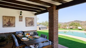 Un patio exterior con una mesa de comedor, sillas y una piscina.