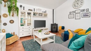 Una sala de estar moderna con televisor, muebles blancos, chimenea y un reloj en la pared.