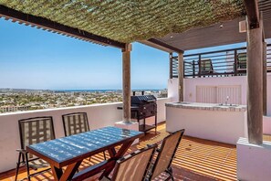 A rooftop terrace with a table, chairs, a grill, and a view of the city. - Cerro Colorado Condo - 1BR Condo in Cabo San Lucas (Cabo San Lucas)
