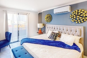 A bedroom with a large bed, a chair, a bedside table with a lamp, and two wall decorations. - Cerro Colorado Condo - 1BR Condo in Cabo San Lucas (Cabo San Lucas)