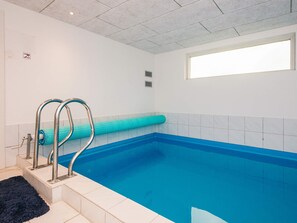 A swimming pool with a blue interior, a window on the right, and a ceiling with a light fixture. - 4 Star Holiday Home in Juelsminde (Horsens)
