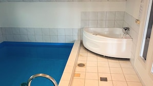 A swimming pool with a blue floor, a white bathtub, and tiled walls. - 4 Star Holiday Home in Juelsminde (Horsens)