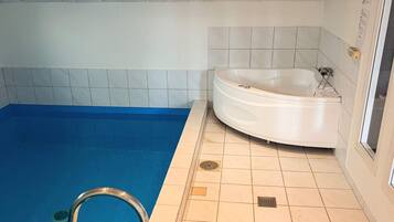 Uma piscina com piso azul, banheira branca e paredes revestidas de azulejos.