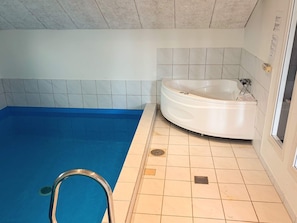 Ein Swimmingpool mit blauem Boden, einer weißen Badewanne und gefliesten Wänden.