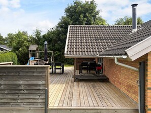 Eine Holzterrasse mit einer Patio-Ecke, einer Ziegelwand und einem Schornstein.