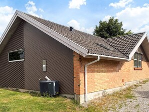Ein Wohngebäude mit einem Satteldach, einem Backsteinbereich und einem Fenster.