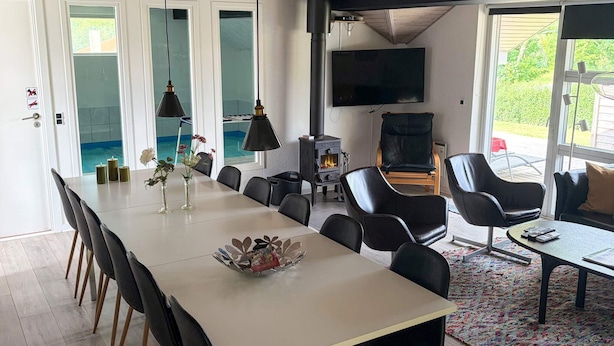 A modern dining area with a long table, black chairs, and a fireplace. - 4 Star Holiday Home in Juelsminde (Horsens)