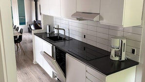 A modern kitchen with white cabinets, a black countertop, a built-in dishwasher, and a coffee maker. - 4 Star Holiday Home in Juelsminde (Horsens)