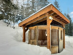 A wooden cabin with a snow-covered roof, surrounded by trees and snow. - Le Nordique | Private Sauna & Spa | Lake access (Val-des-Lacs)