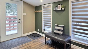 A room with a bench, a door, and a window with blinds. - Le Nordique | Private Sauna & Spa | Lake access (Val-des-Lacs)