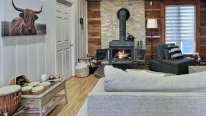 A cozy living room with a stone wall, a fireplace, a sofa, and a drum set. - Le Nordique | Private Sauna & Spa | Lake access (Val-des-Lacs)