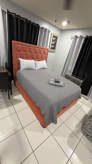 Una camera da letto con un letto, un comodino, una sedia e una finestra con tende.