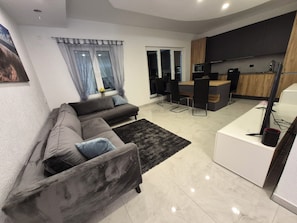 Ein modernes Wohnzimmer mit einer Couch, einem Teppich und einer Küchenzeile mit einer Theke und Stühlen.
