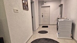 A hallway with a washing machine, a door, and a power outlet on the wall.