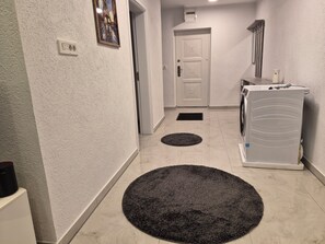 Ein Flur mit Waschmaschine, Tür und Steckdose an der Wand.