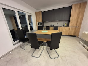 Een moderne keuken met een eettafel, stoelen en uitzicht op de stad 's nachts.