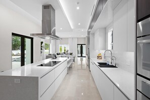 Una cocina moderna con una isla central, electrodomésticos de acero inoxidable y vistas al exterior.