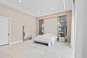 Une chambre à coucher moderne, comprenant un lit, des tables de chevet, un miroir et une armoire intégrée.