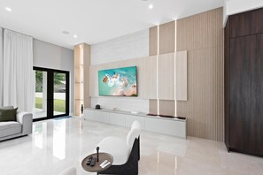Una sala de estar moderna con un televisor de pantalla plana grande, un sofá, una mesita de centro y un diseño minimalista.