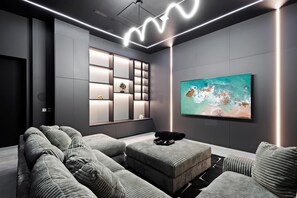 Un salon moderne avec un canapé d’angle, un téléviseur à écran plat et une étagère murale agrémentée d’objets décoratifs.