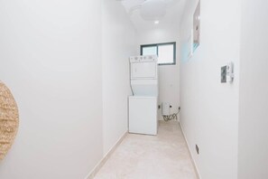 Un cuarto de lavado con lavadora y secadora apiladas, una ventana y un enchufe.