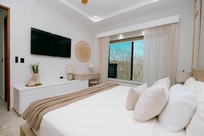 A modern bedroom with a large bed, a flat-screen TV, a desk, and a window with a view. - Luxery Apartment | Pool | Playa Flamingo #1 (Brasilito)