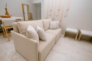 Una sala de estar en tonos neutros, con un sofá, una mesita y un banco.