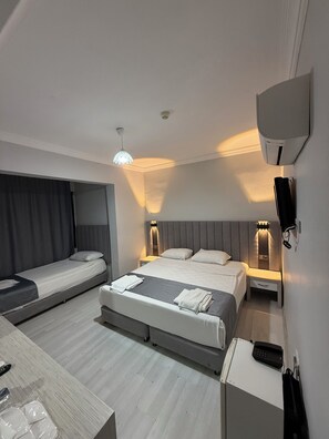 Una habitación de hotel con dos camas, un escritorio, un televisor y una lámpara de techo.