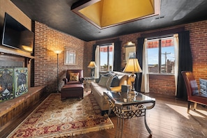 A cozy living room with a fireplace, a sofa, a coffee table, and a television. - Upscale, Spacious Apt in the Heart of Downtown. Walk to Restaurants & Breweries! (Hendersonville)