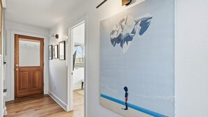 Un couloir avec une porte en bois, des tableaux encadrés et une grande fresque murale.