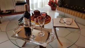 Ein Tisch mit einer Weinflasche, Gläsern, einer Serviertschale, einem Buch und einer Fernbedienung.