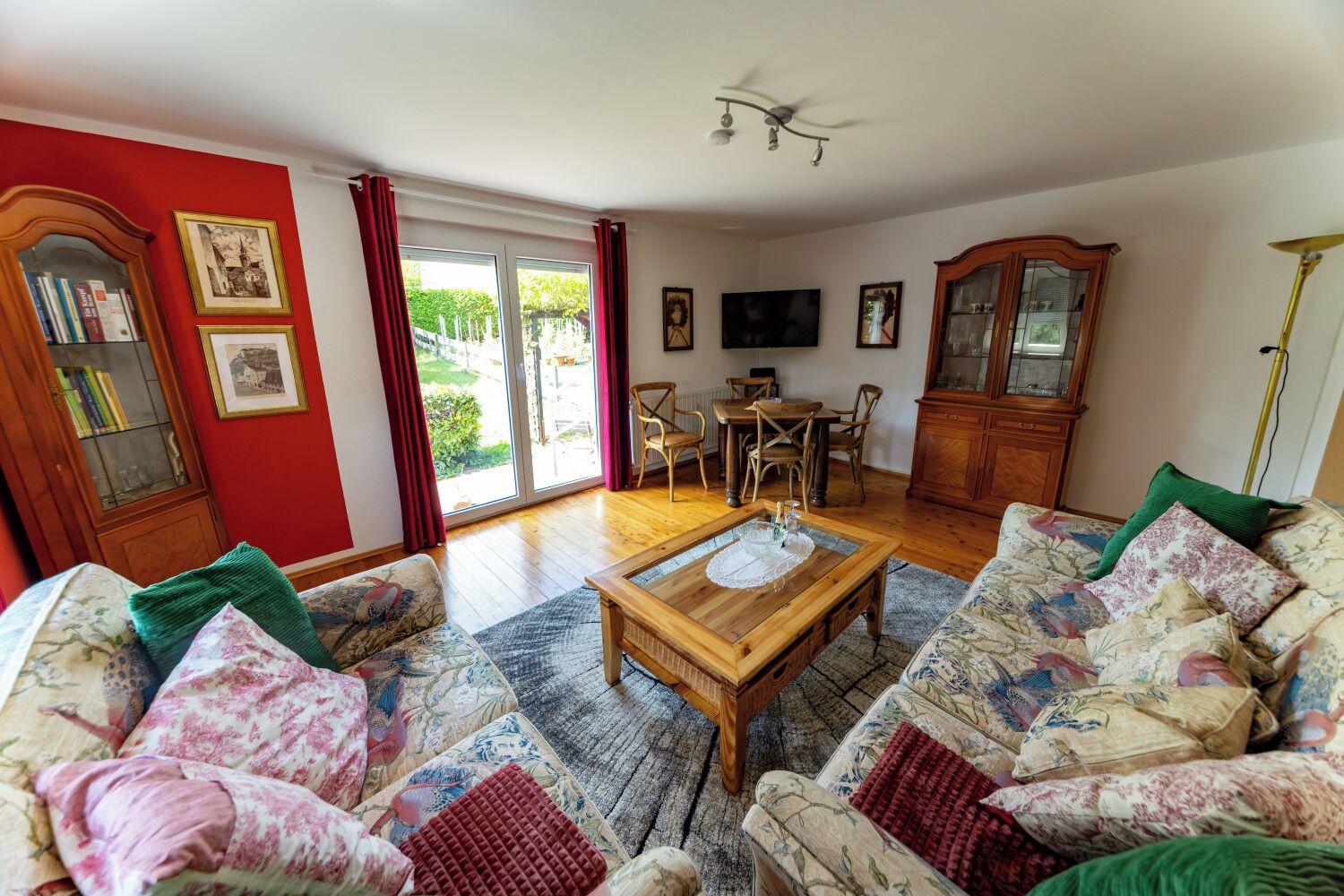 A living room with a sofa set, a wooden coffee table, a television, and a dining area with chairs.