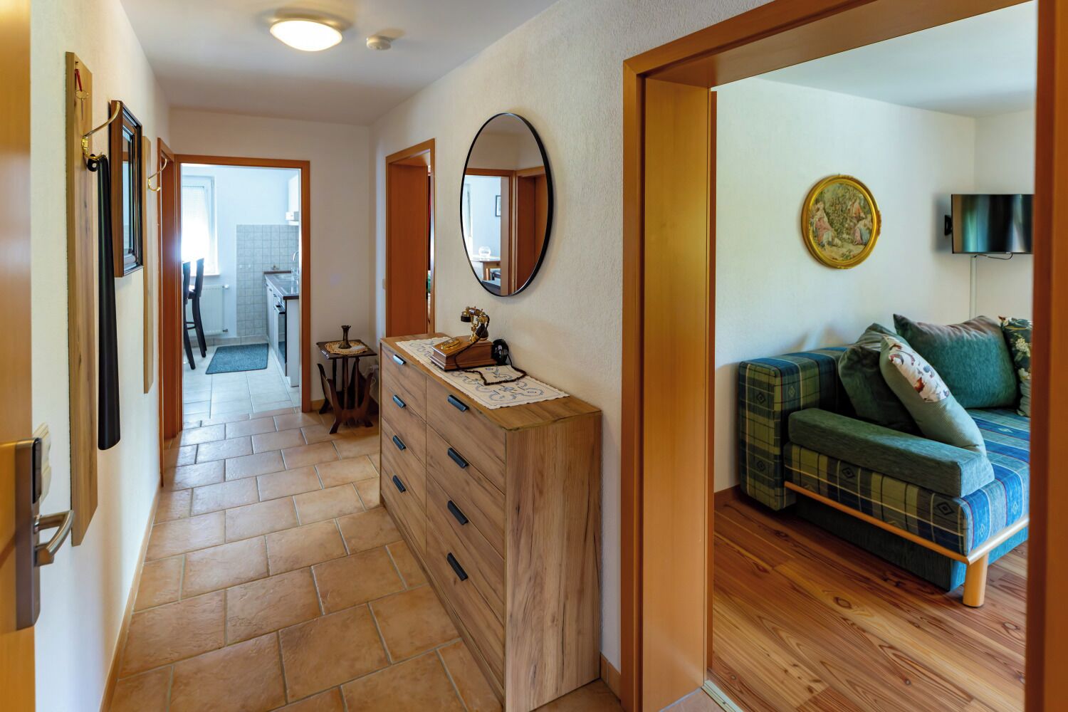 A hallway with a wooden dresser, a mirror, and a sofa with cushions.