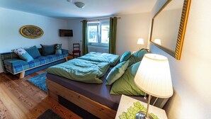 Un dormitorio con cama, sofá, lámpara, espejo y ventana.