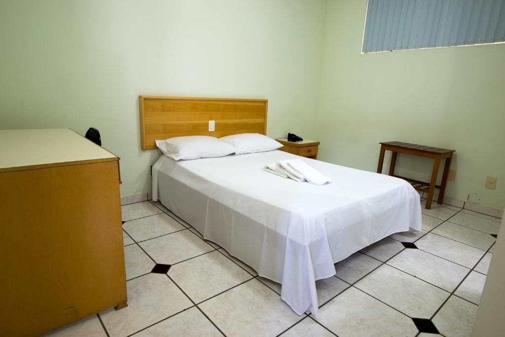 A single bed with a wooden headboard, a bedside table, a nightstand, and a small wooden table.