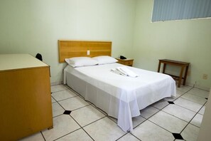 A single bed with a wooden headboard, a bedside table, a nightstand, and a small wooden table.