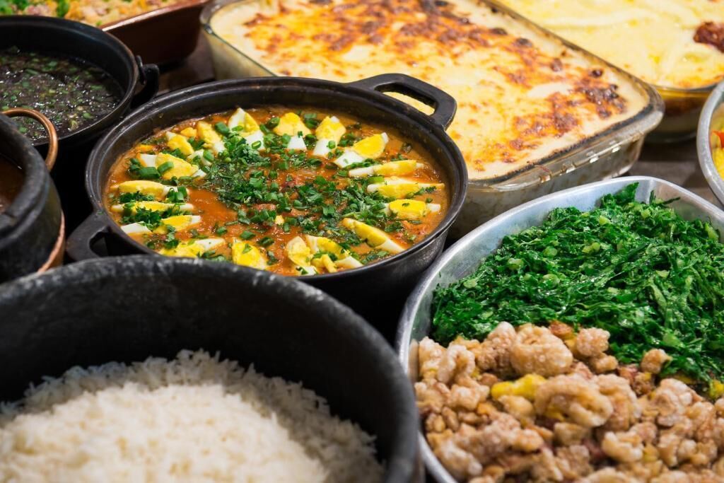 A variety of dishes including a stew with eggs, a casserole, and a bowl of rice.