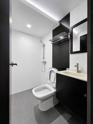 Une salle de bain moderne équipée de toilettes, d’une douche et d’un lavabo.